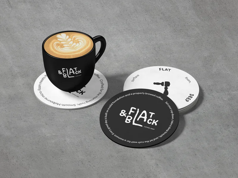 A black cup on a white coaster, beside two more coasters — one white with a ring of small type, one black with the wordmark.