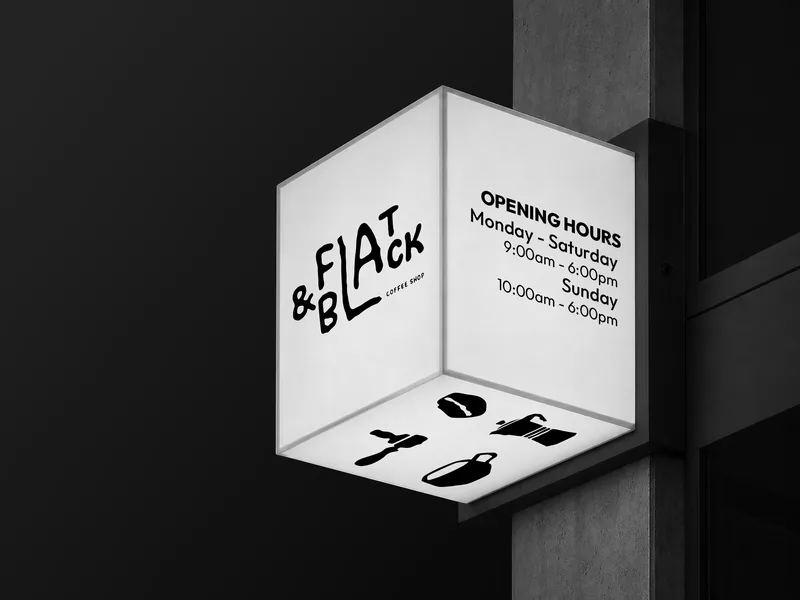 An illuminated cube sign on a dark wall at night, wordmark on one face and opening hours on the next.