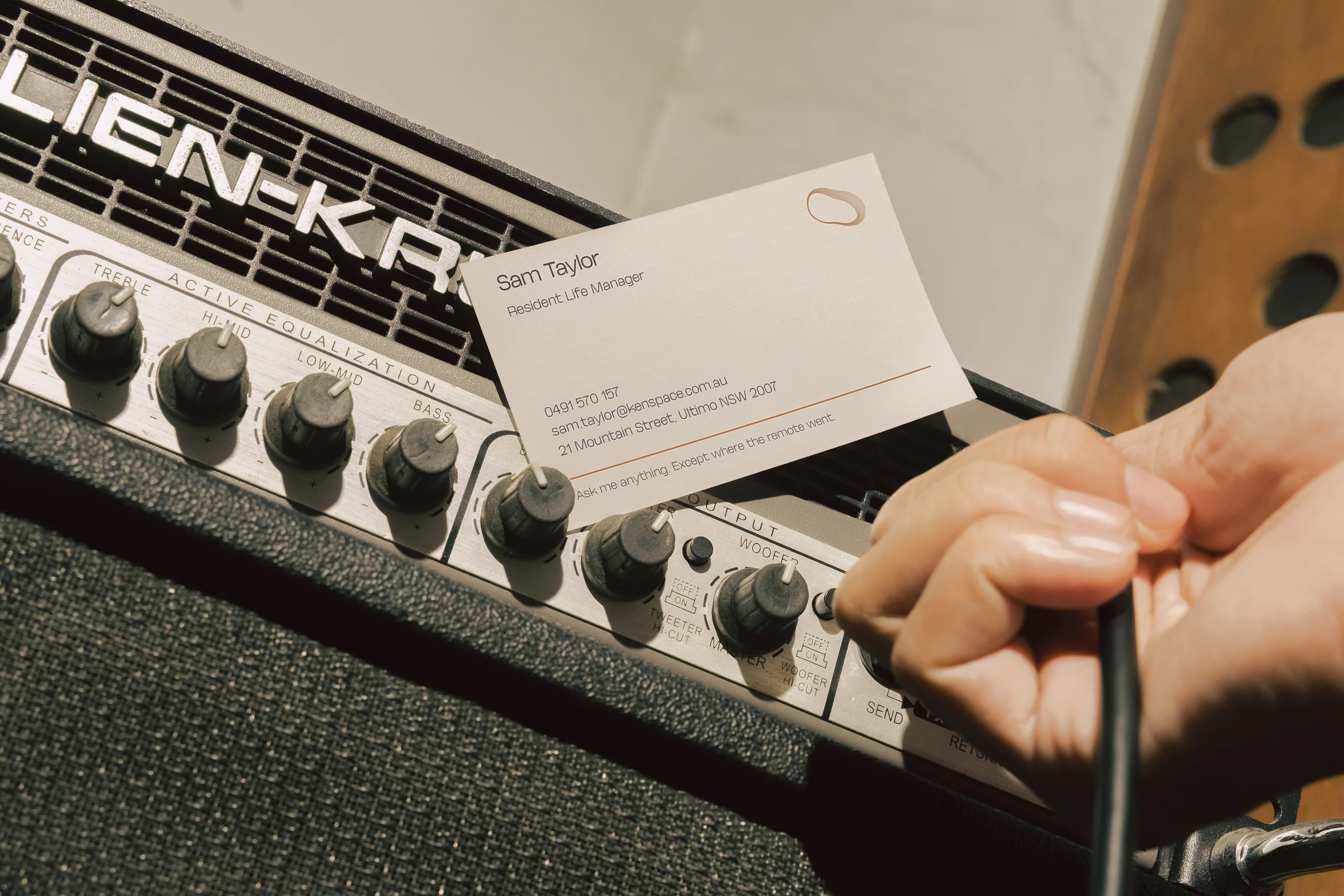 A staff business card held against a guitar amplifier.