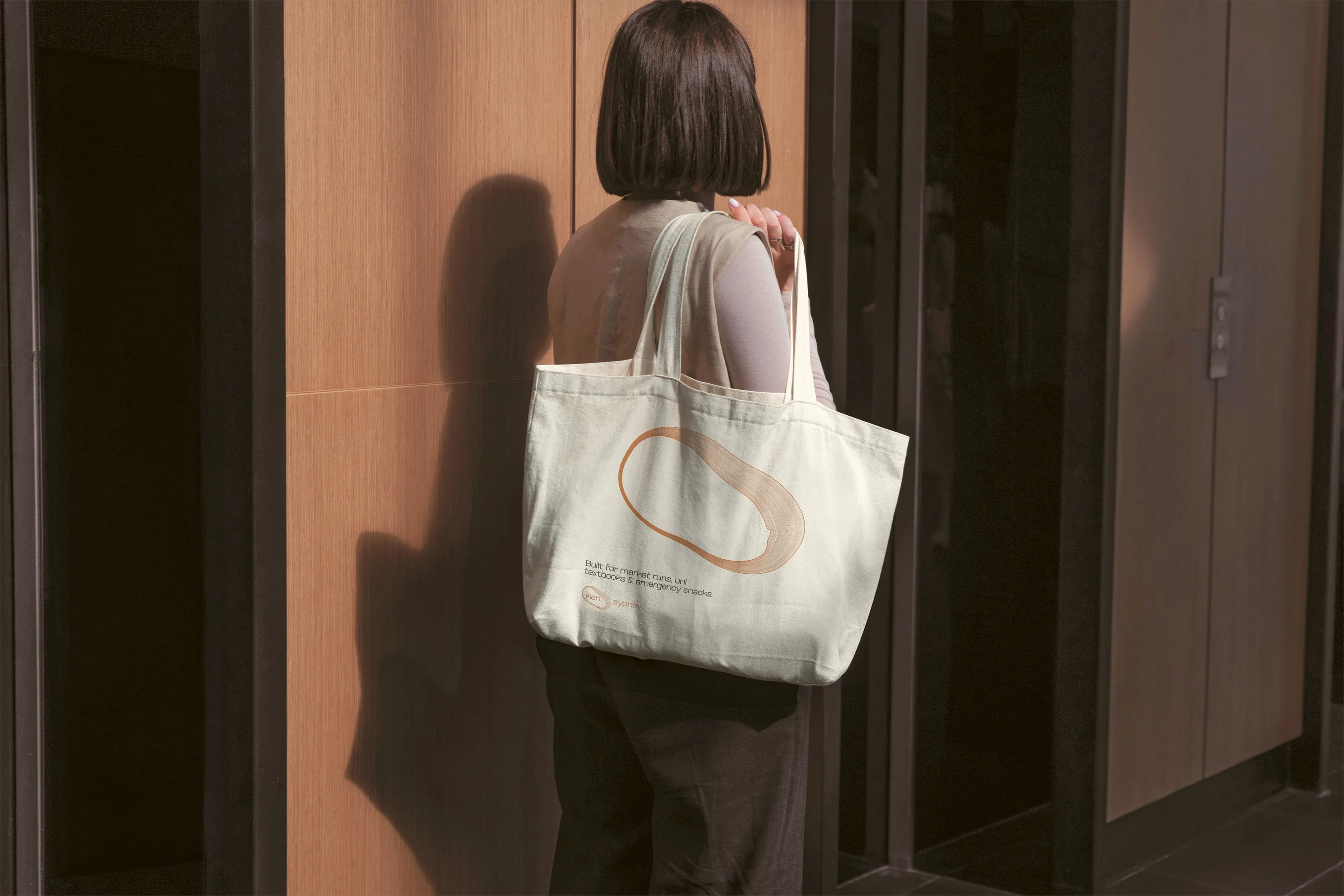 A resident carrying the cream welcome tote with the copper ring printed on it.