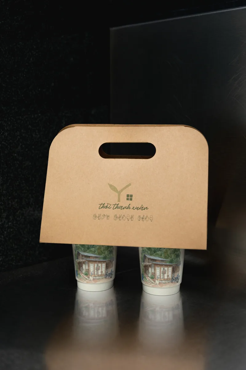 Kraft cup carrier with the Youth Home mark, two watercolour cups seated in it